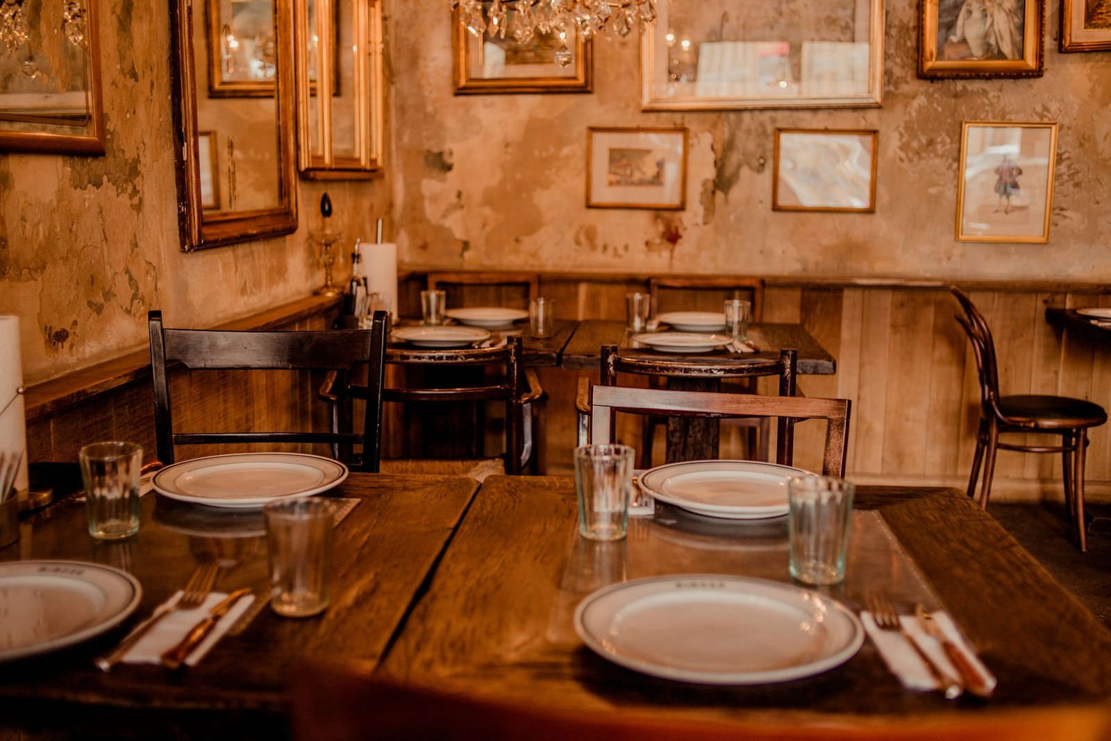 Salle de bistrot rustique, tables en bois dressées et cadres aux murs
